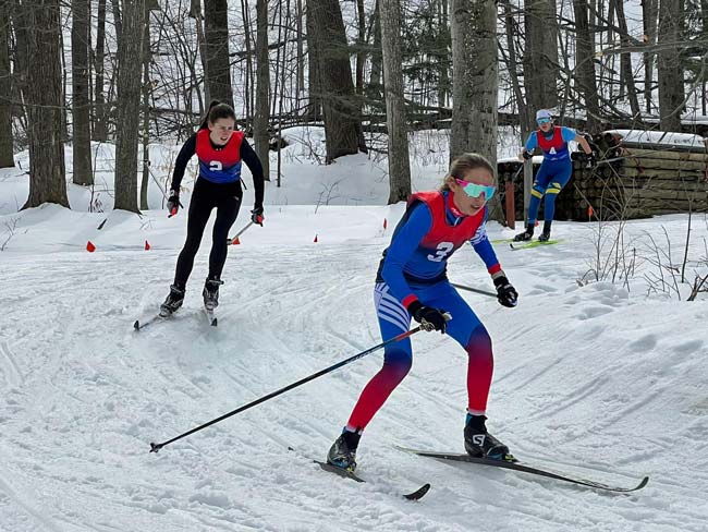 Three cross country skiers rounding a fast downhill corner