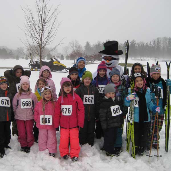 Kids on cross country skis with Frosty the Snowman